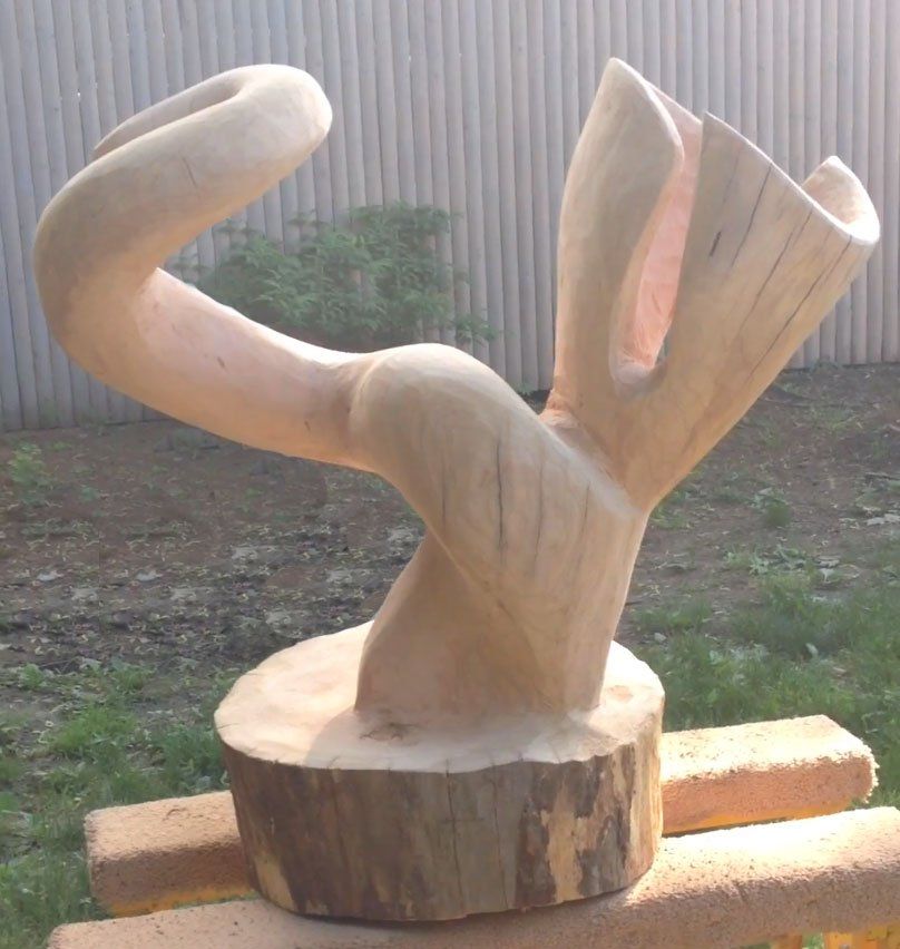 A wooden sculpture is sitting on a brick railing