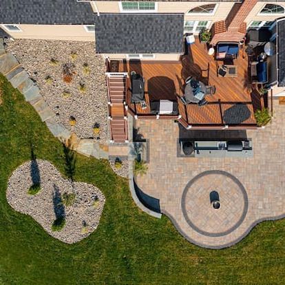 Spacious outdoor living area featuring multiple zones including a dining area, fire pit, and outdoor kitchen, designed to maximize backyard enjoyment and functionality