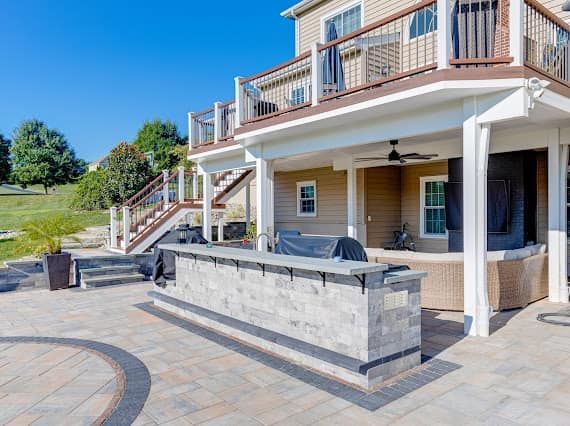 A large house with a patio with a grill and stairs.