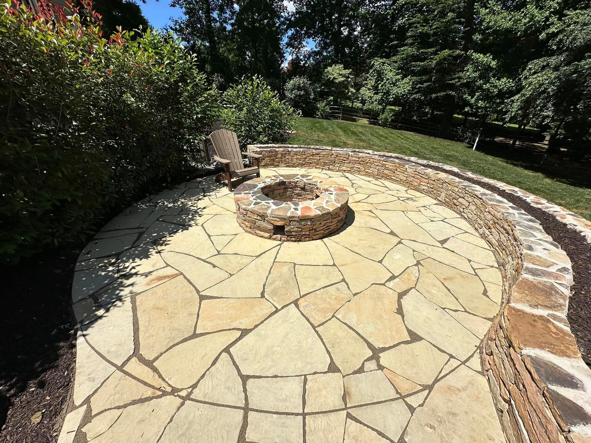 A stone patio with a fire pit in the middle of it.