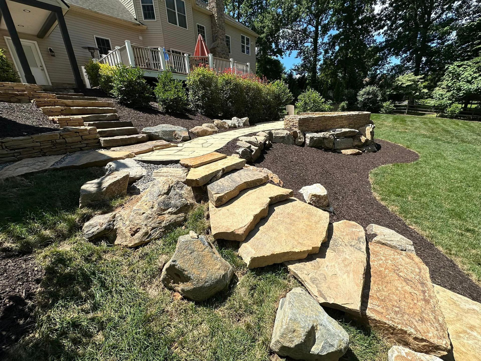 A stone walkway leading to a house in a backyard.