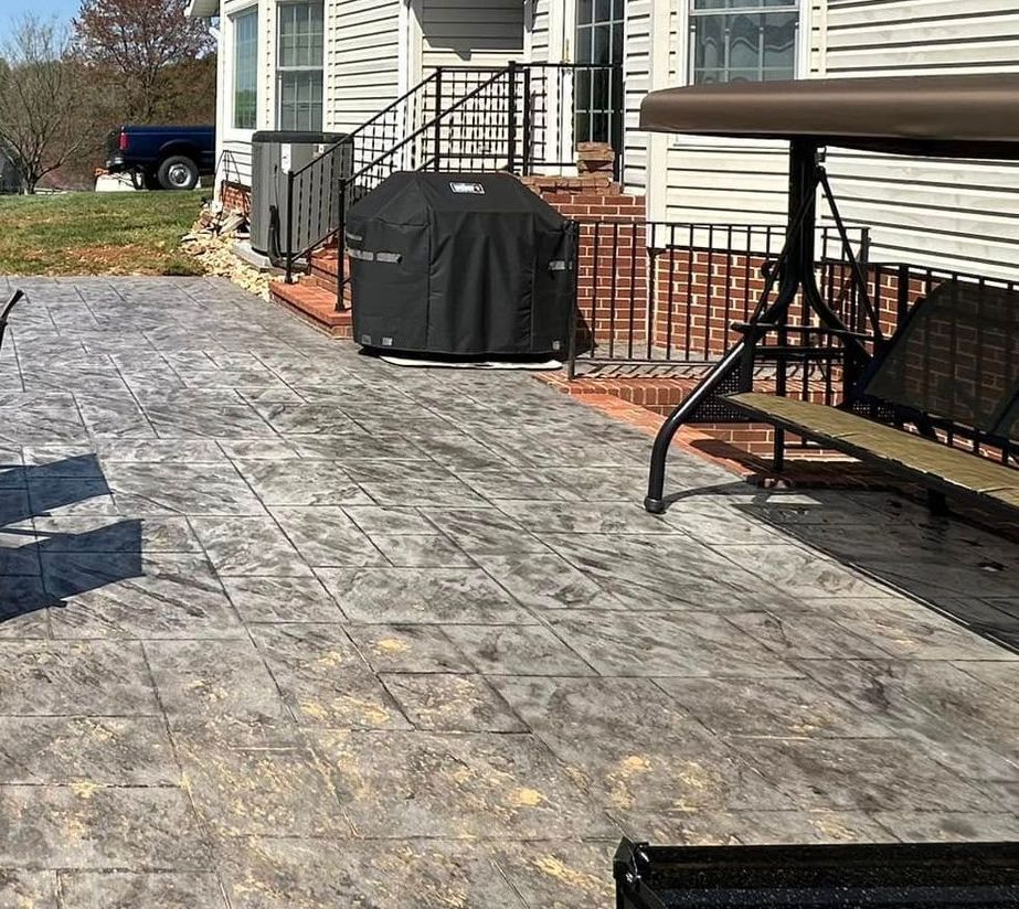 A patio with a swing and a grill in front of a house.