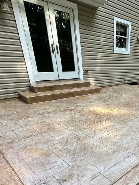 A patio with a stained concrete floor and stairs in front of a house.