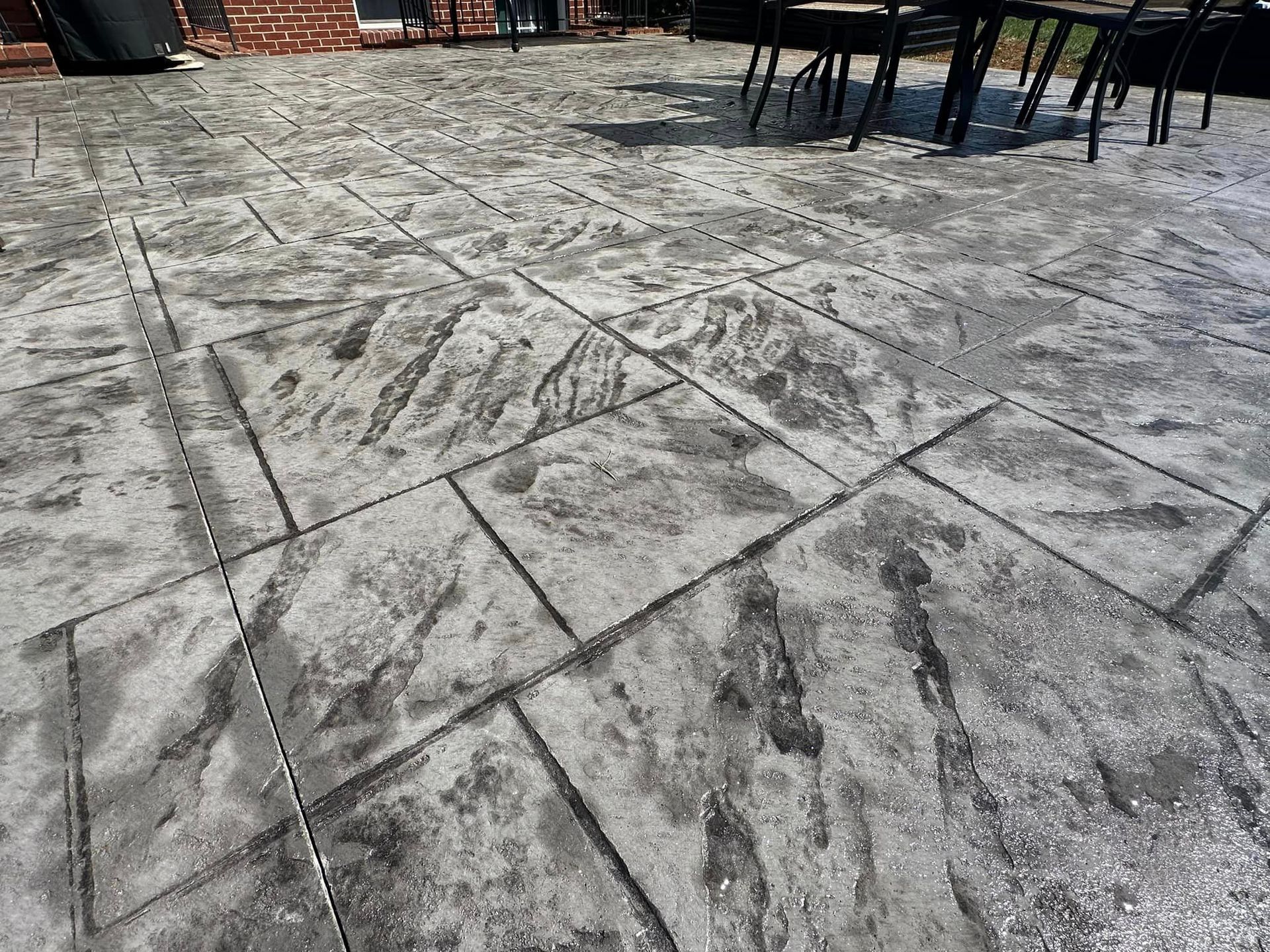 A close up of a concrete patio with a table and chairs on it.