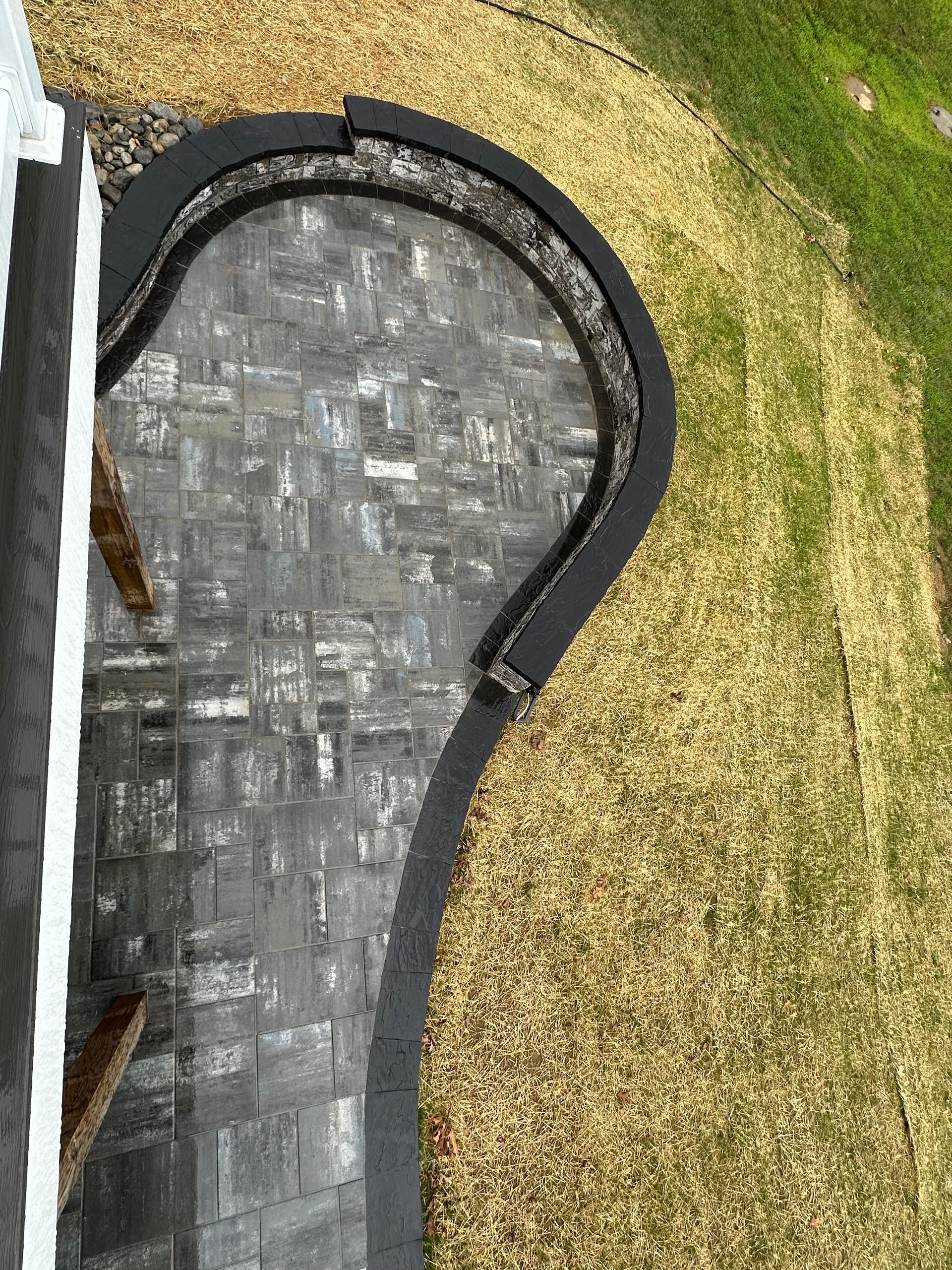 Aerial view of a beautifully designed hardscaping project featuring a new patio and retaining wall in a Maryland backyard.