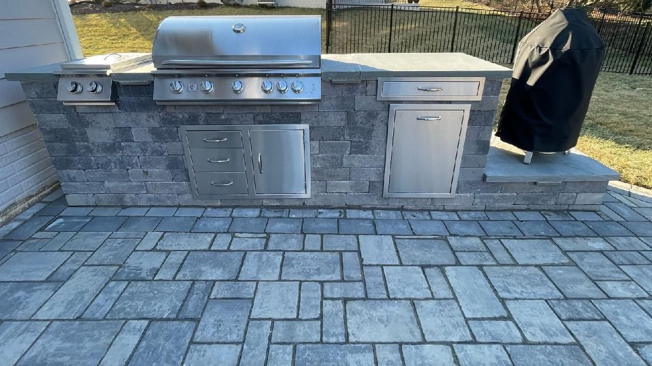 A grill is sitting on top of a brick patio.