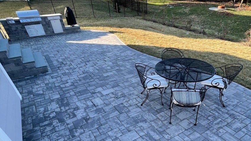 A patio with a table and chairs and a grill.