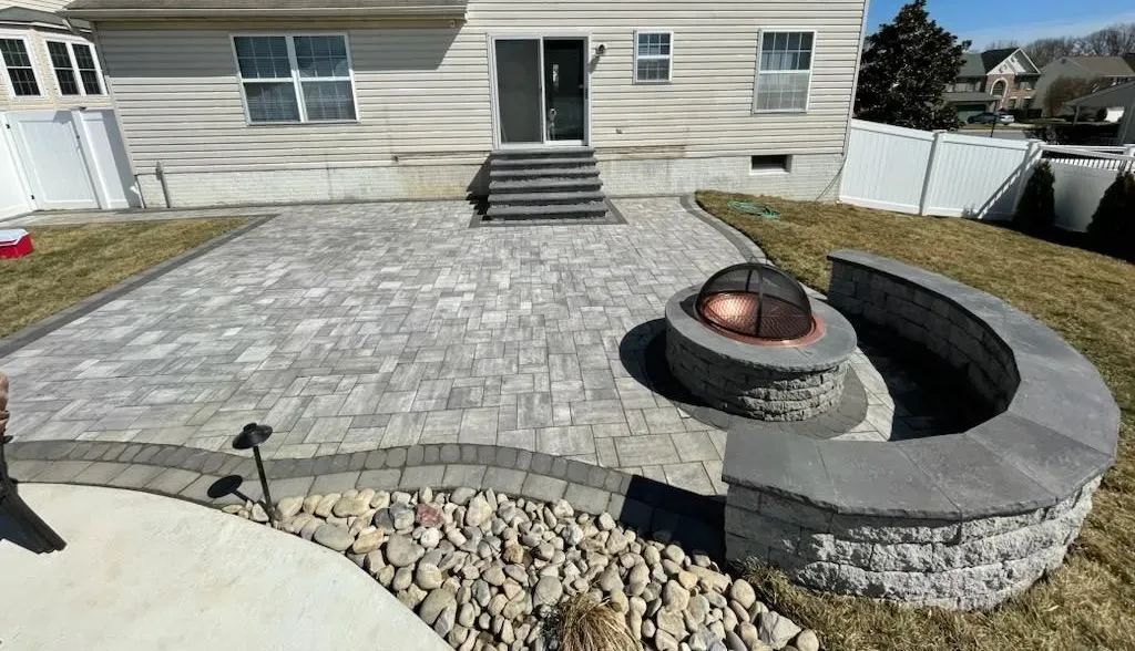 Custom stone patio and fire pit installation designed and built by Xscape 2 Nature