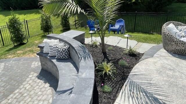 A patio with a curved bench , chairs , and a palm tree.