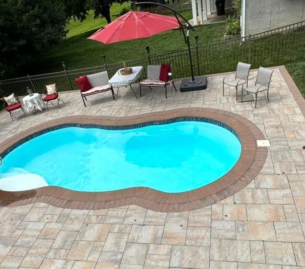 A large swimming pool surrounded by chairs tables and umbrellas