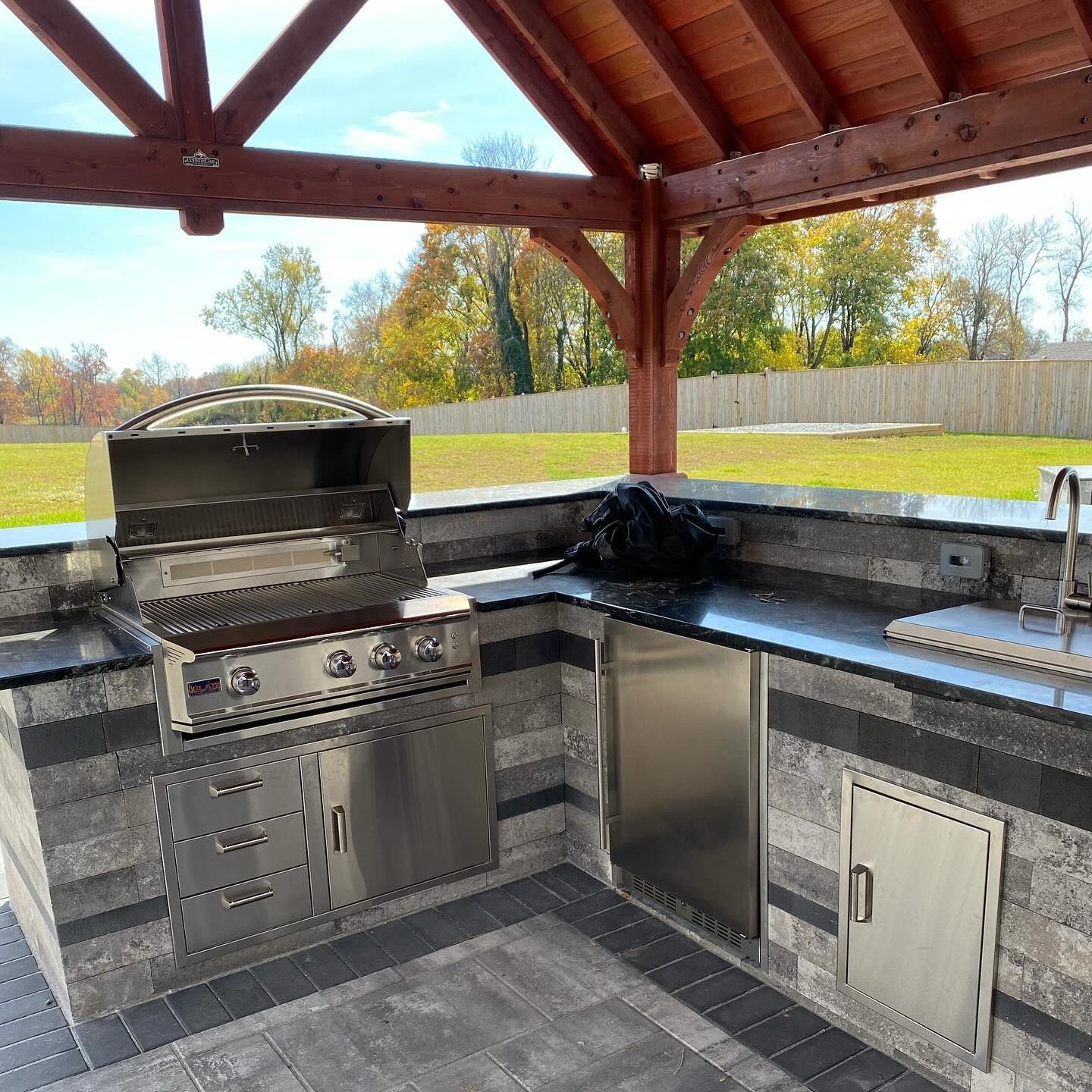 An outdoor kitchen with a stainless steel grill and a sink