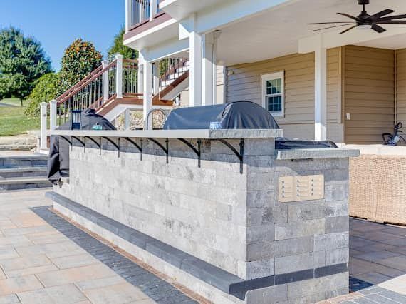 A patio with a grill and a ceiling fan.