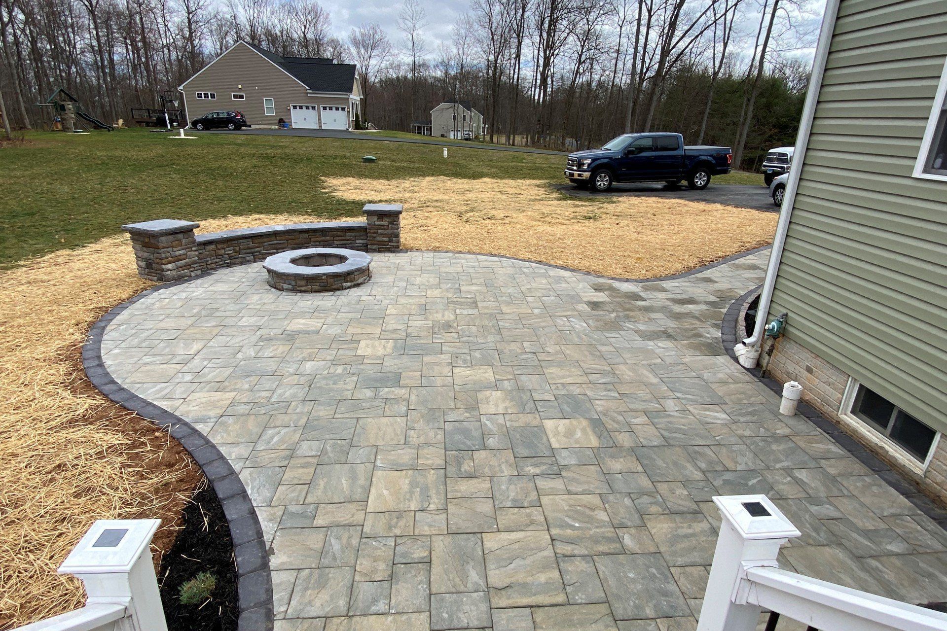A patio with a fire pit and a house in the background.