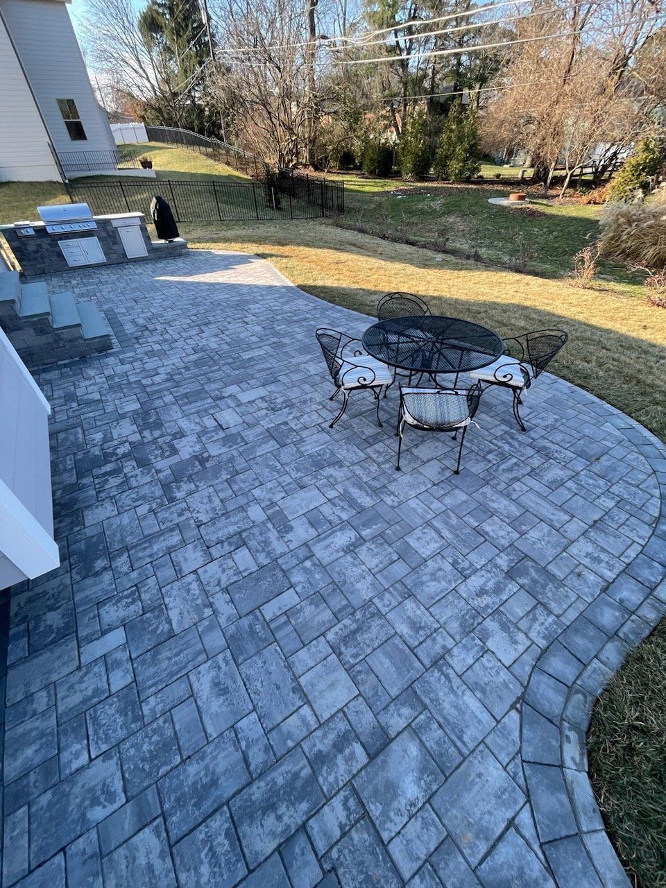 A patio with a table and chairs in the backyard of a house.
