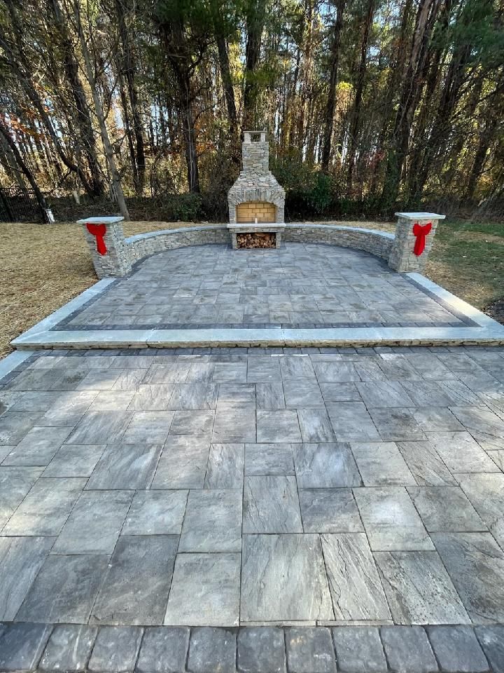 A patio with a fireplace and trees in the background.