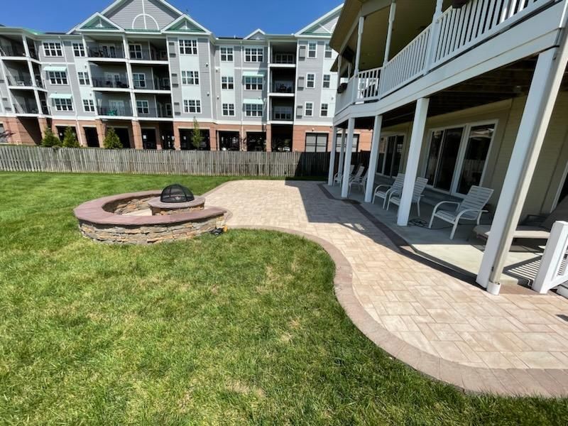 A fire pit is in the middle of a lush green lawn in front of a large building.