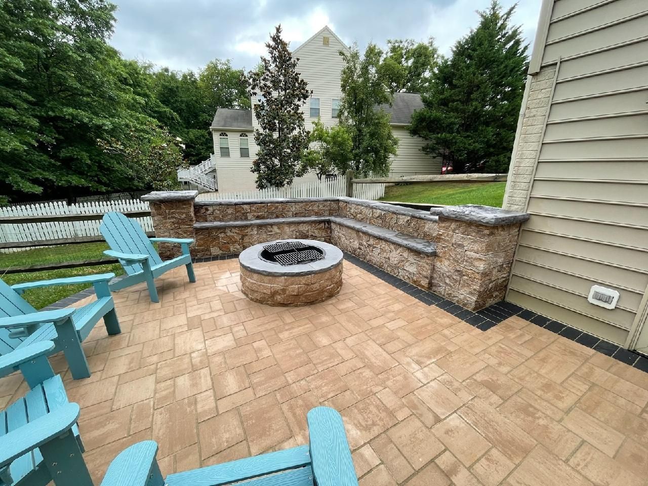 There is a fire pit on the patio with blue chairs.