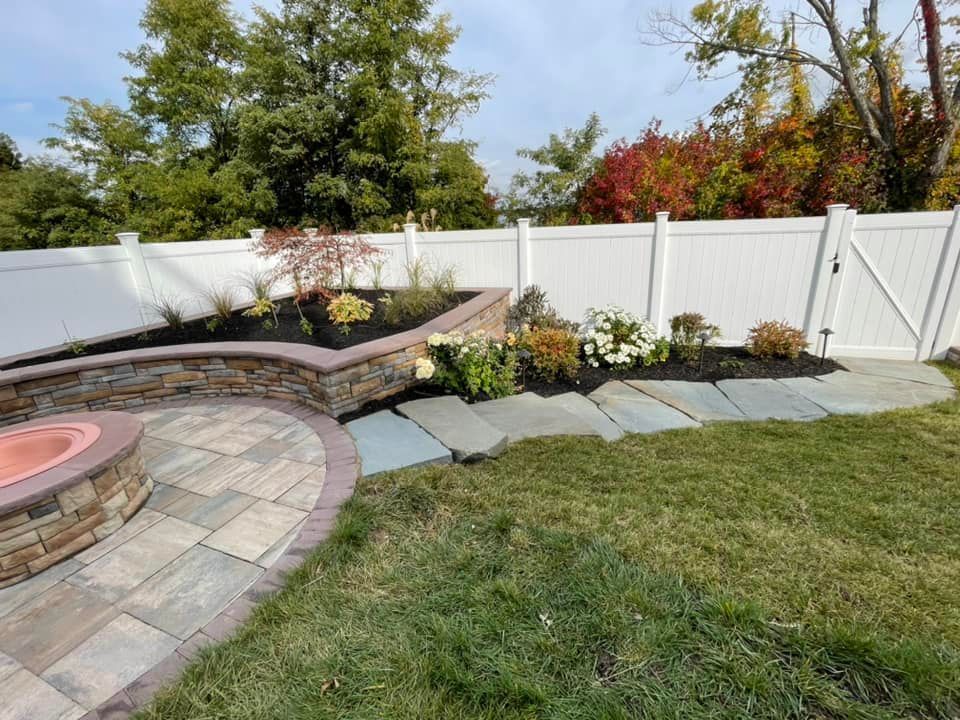 A backyard with a white fence and a fire pit