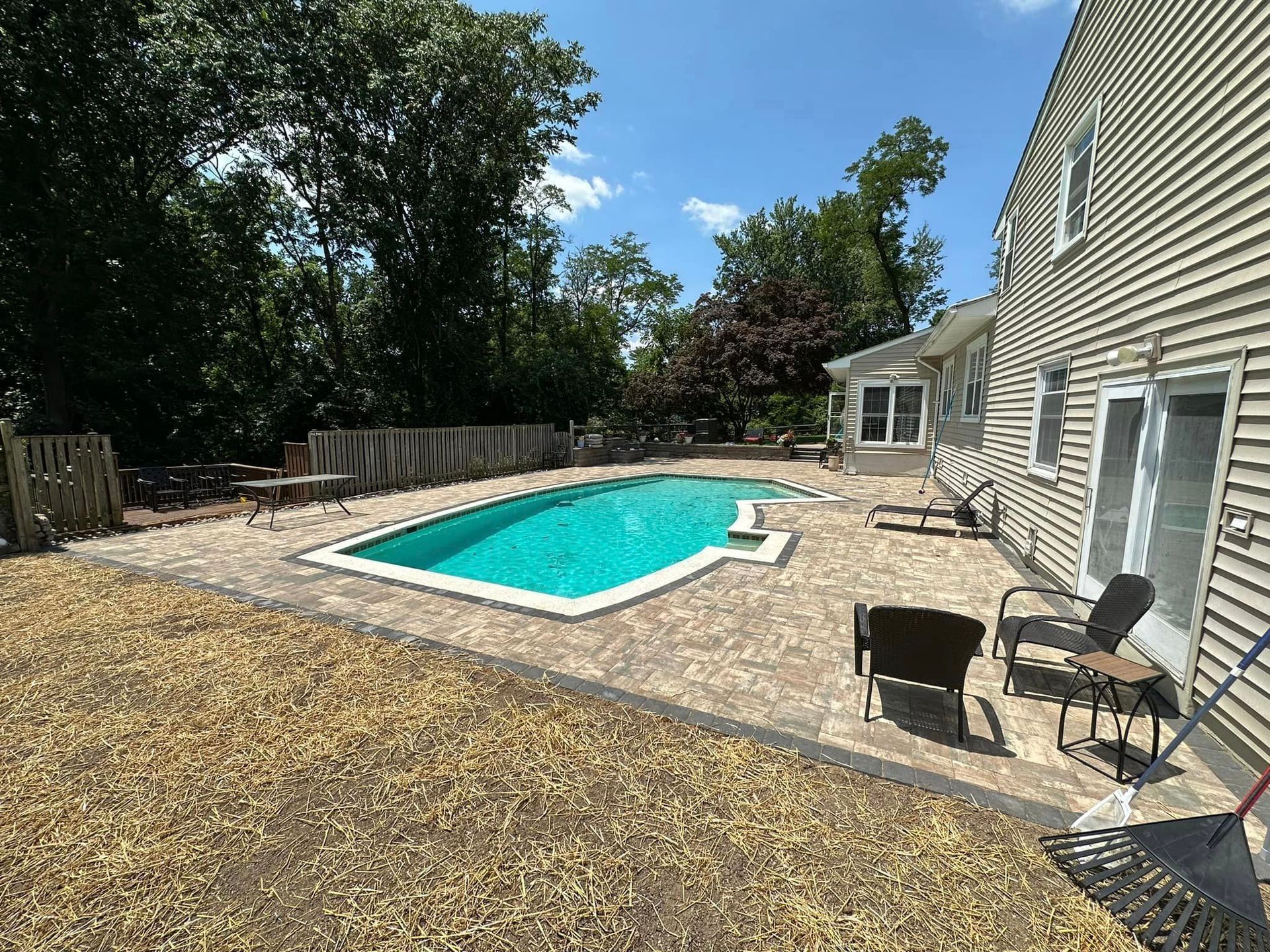 A large swimming pool is in the backyard of a house.