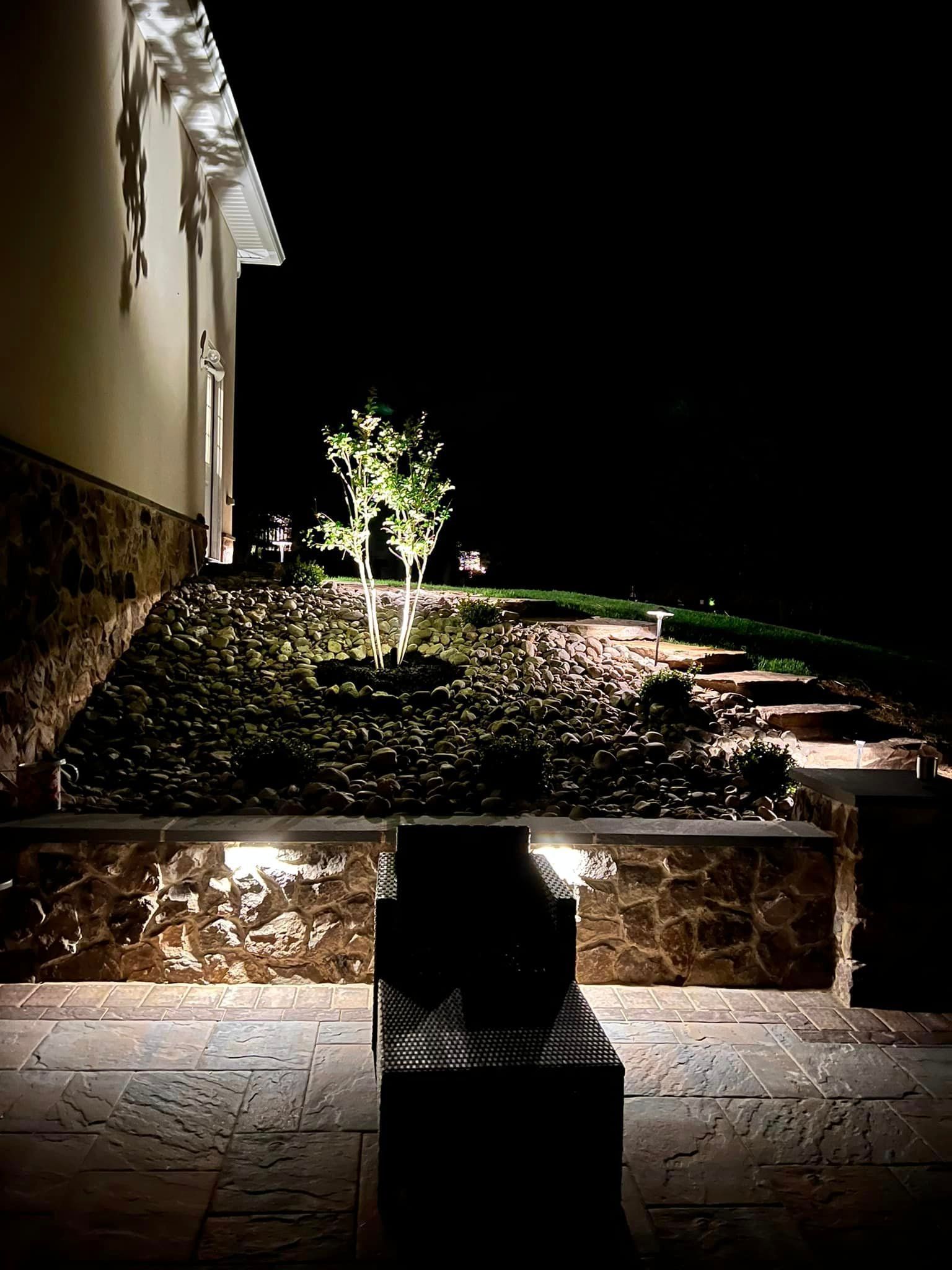 A house is lit up at night and there is a bench in the foreground.