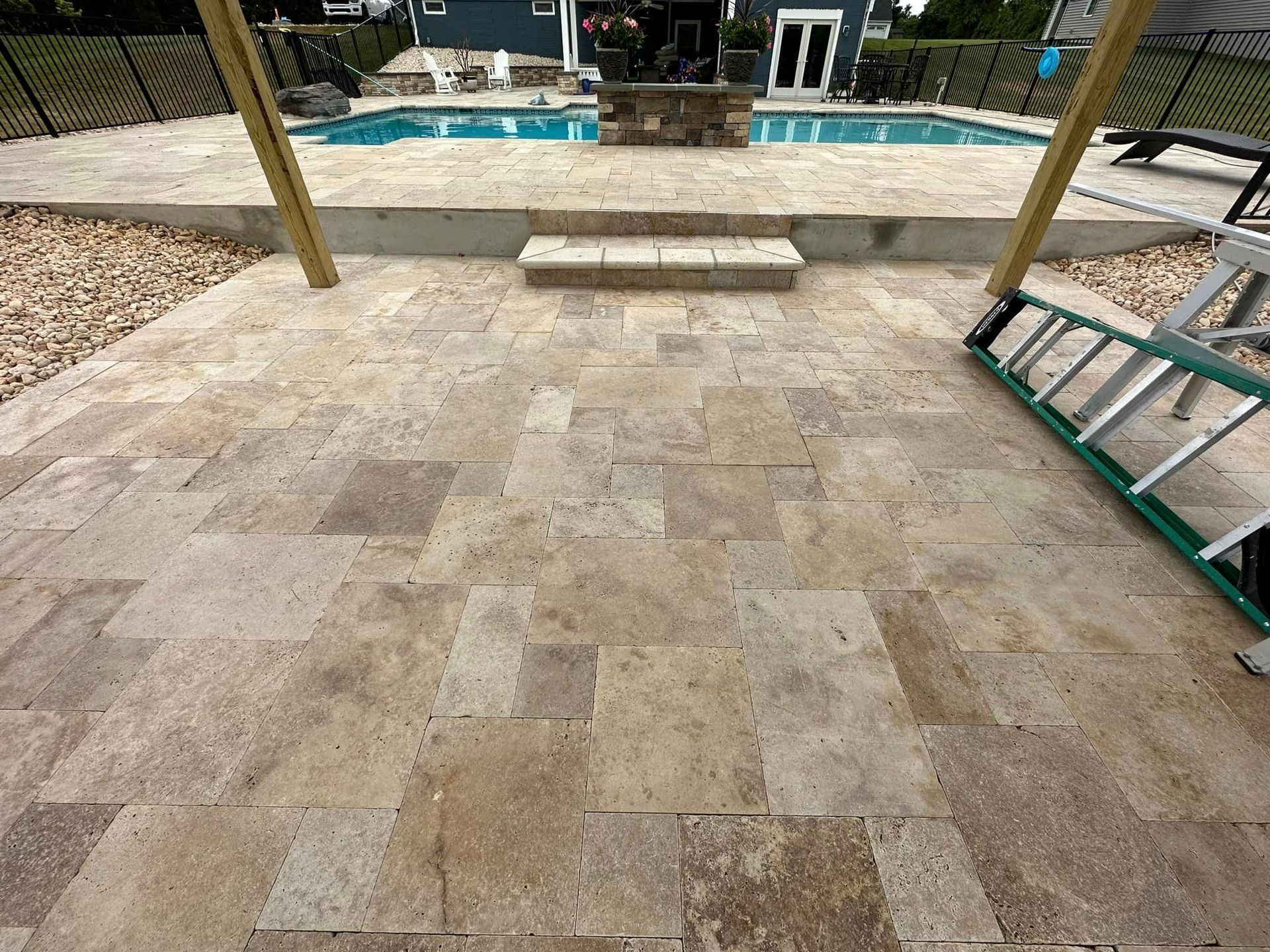 A ladder is sitting on a patio next to a pool.