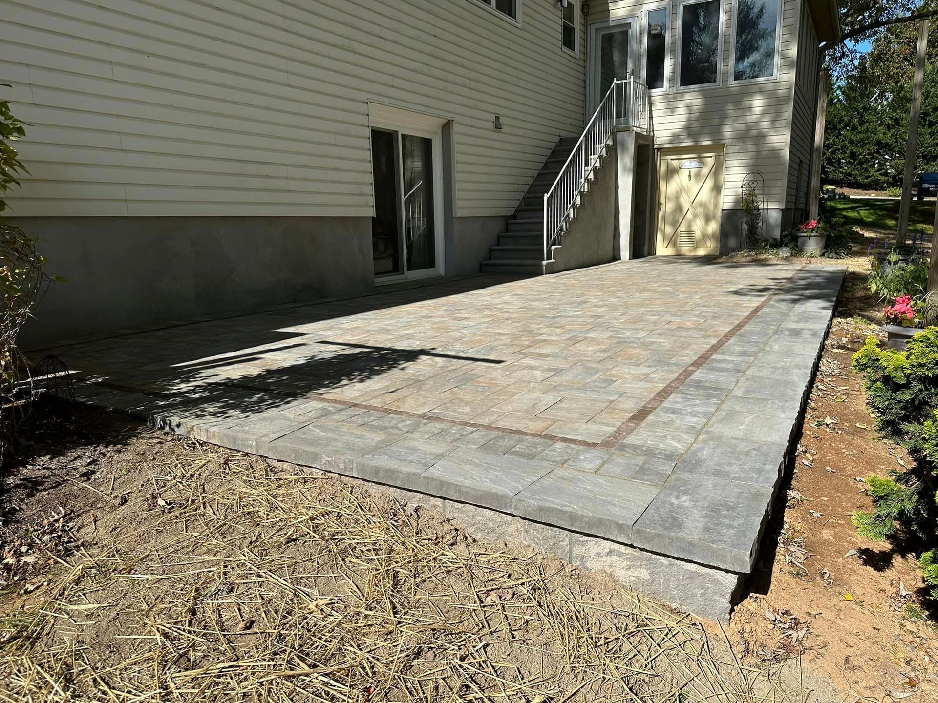 A patio is being built in front of a house with stairs.