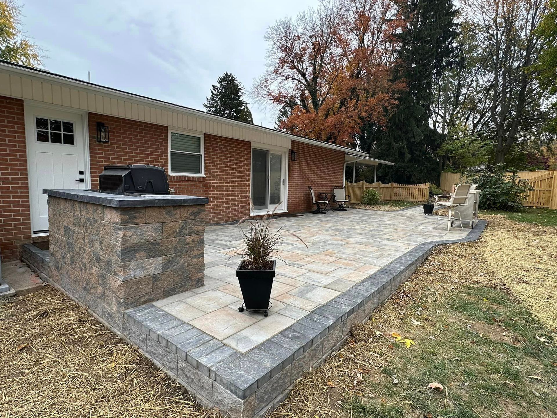 A brick house with a patio and a grill in the backyard.