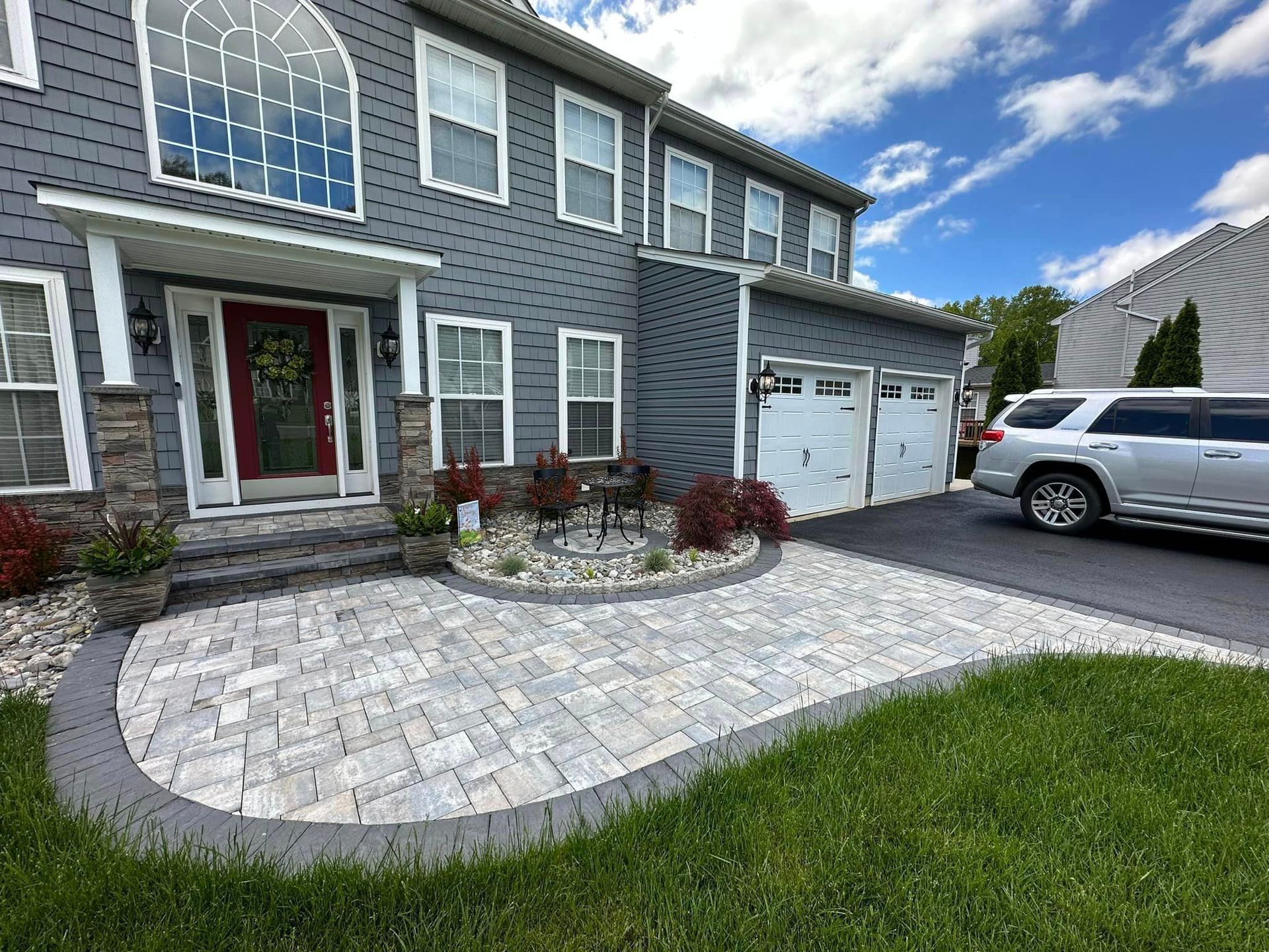 A large gray house with a car parked in front of it.