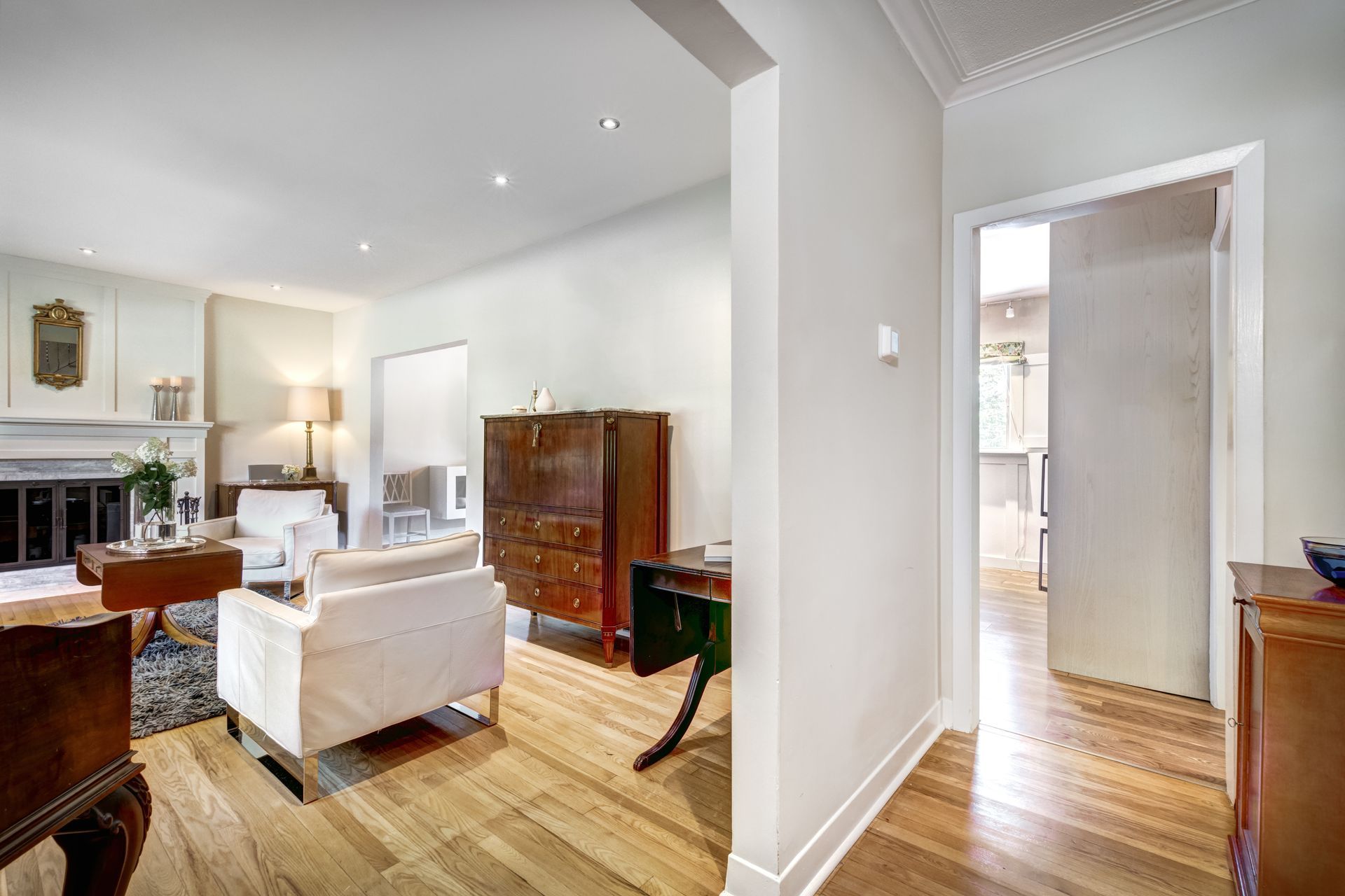 A living room with hardwood floors , white walls and a fireplace.