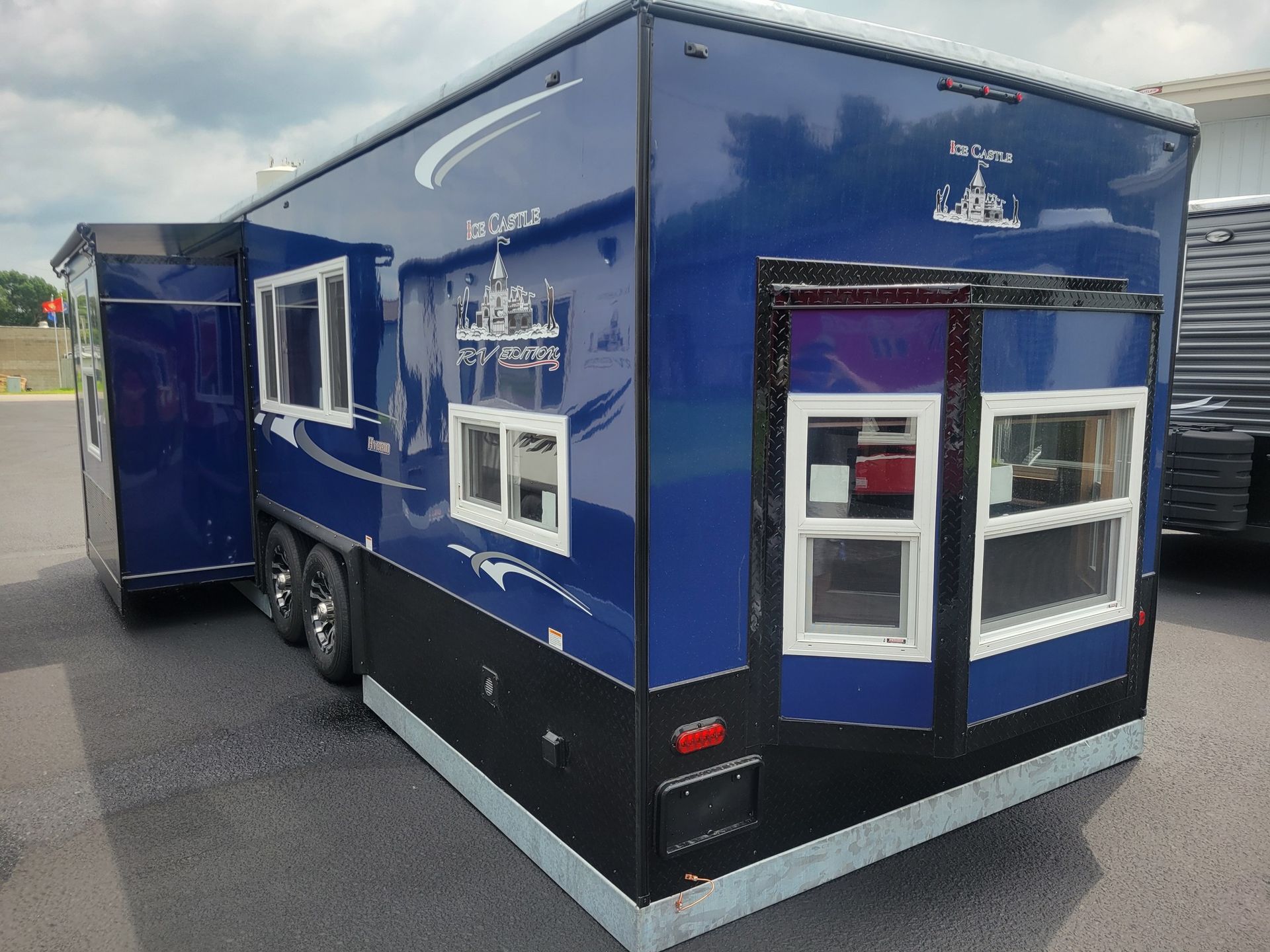 Ice fishing trailer with black and white exterior; logo and red accent details.