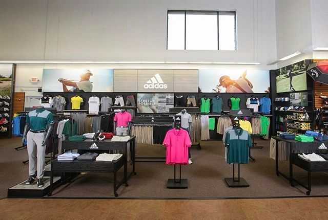 A store with a lot of clothes on display and a sign that says adidas