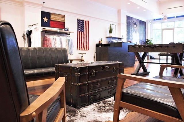 A living room with a couch , chairs , a table and an american flag on the wall.