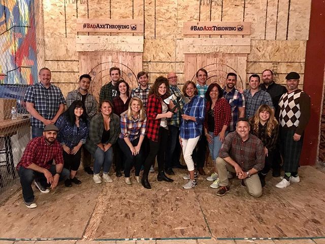 A group of people are posing for a picture in front of a wooden wall.