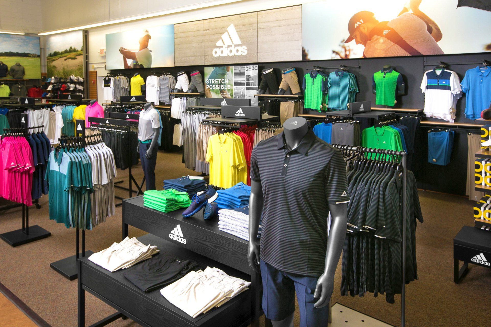 A store filled with lots of shirts and a sign that says adidas