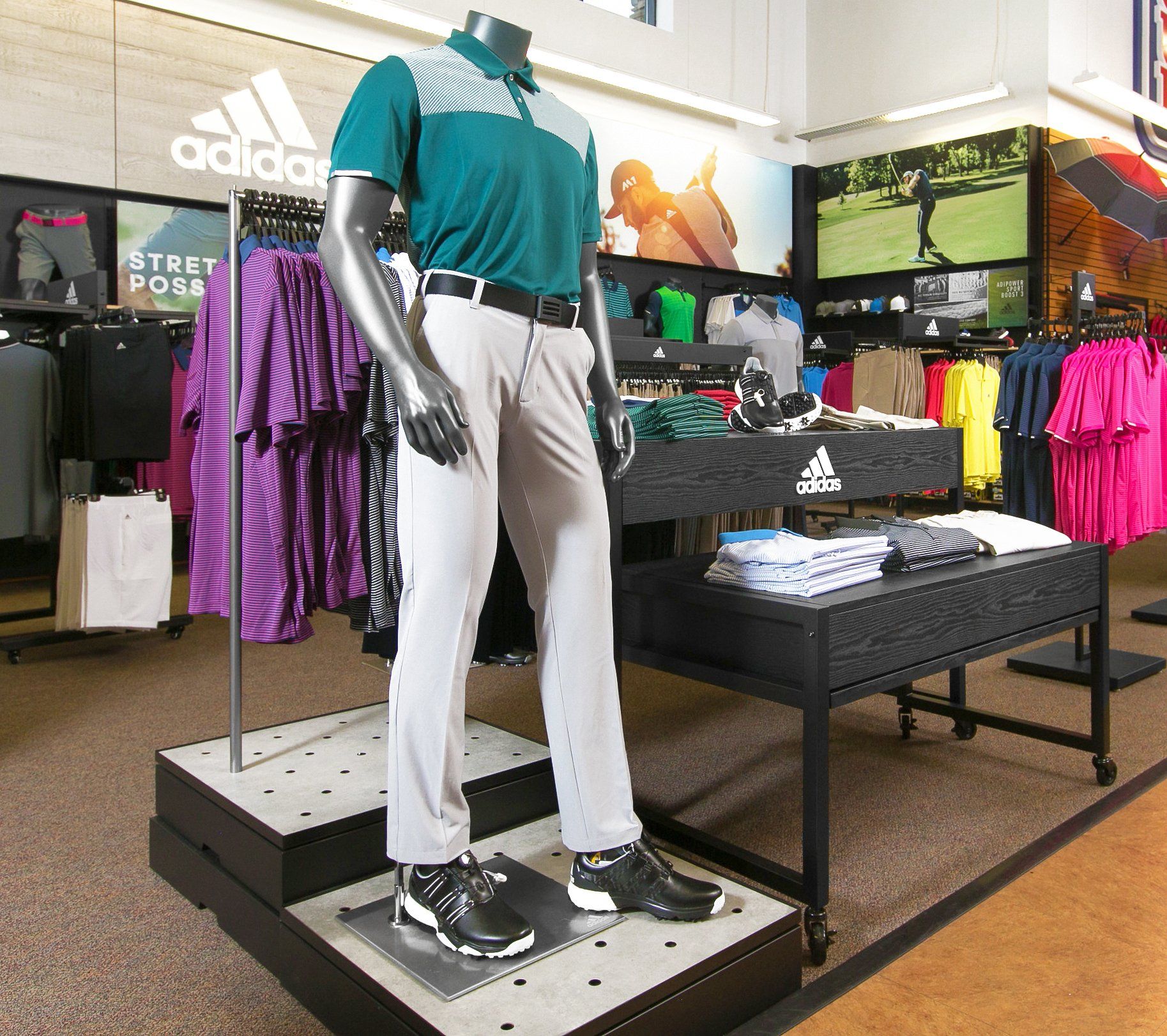 A mannequin wearing a green shirt and grey pants in an adidas store