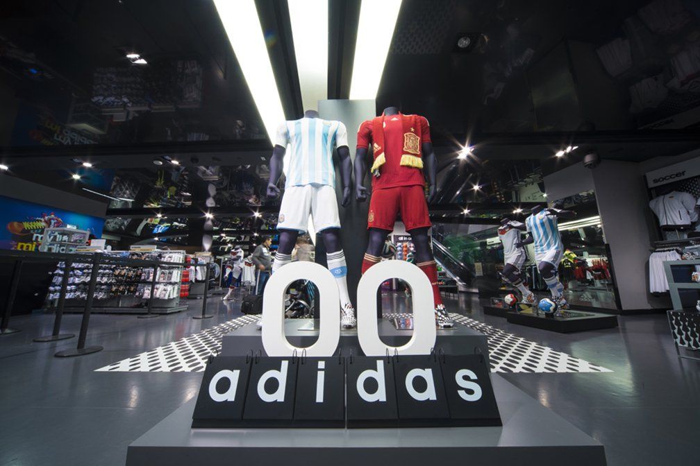 Two mannequins are standing in front of a sign that says adidas.