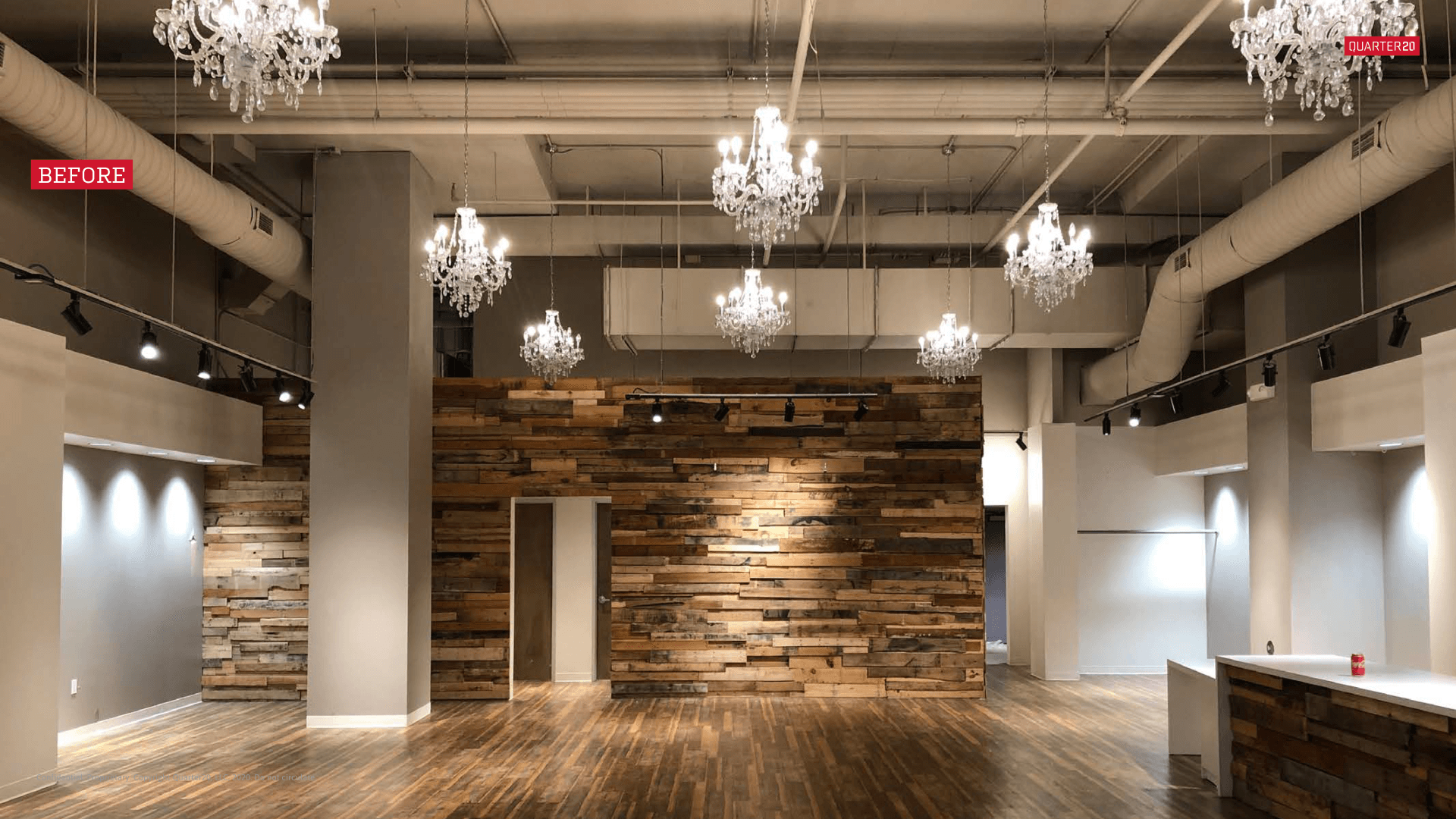 A large empty room with a wooden wall and chandeliers hanging from the ceiling.