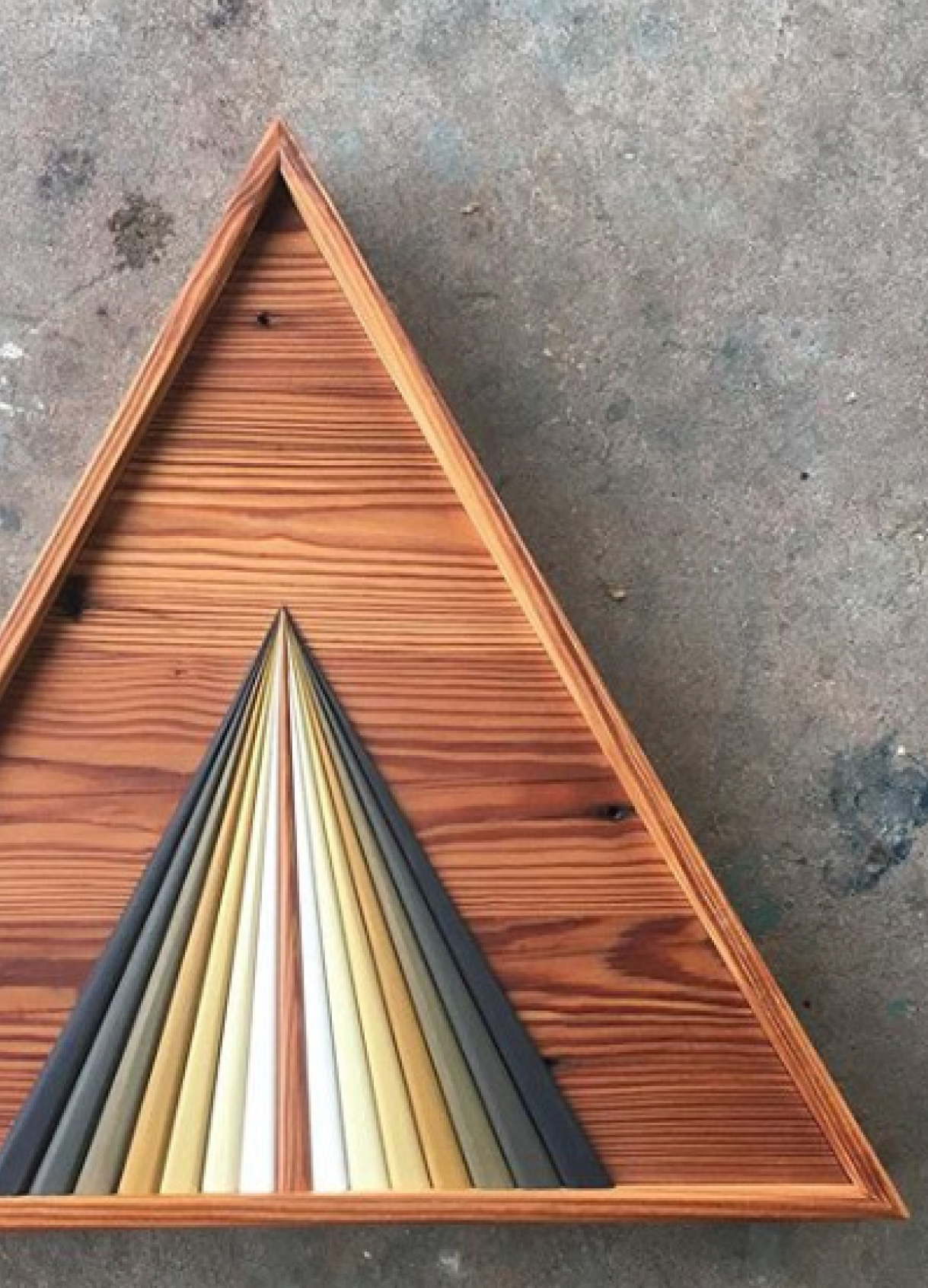 A wooden triangle with a rainbow of colors on it