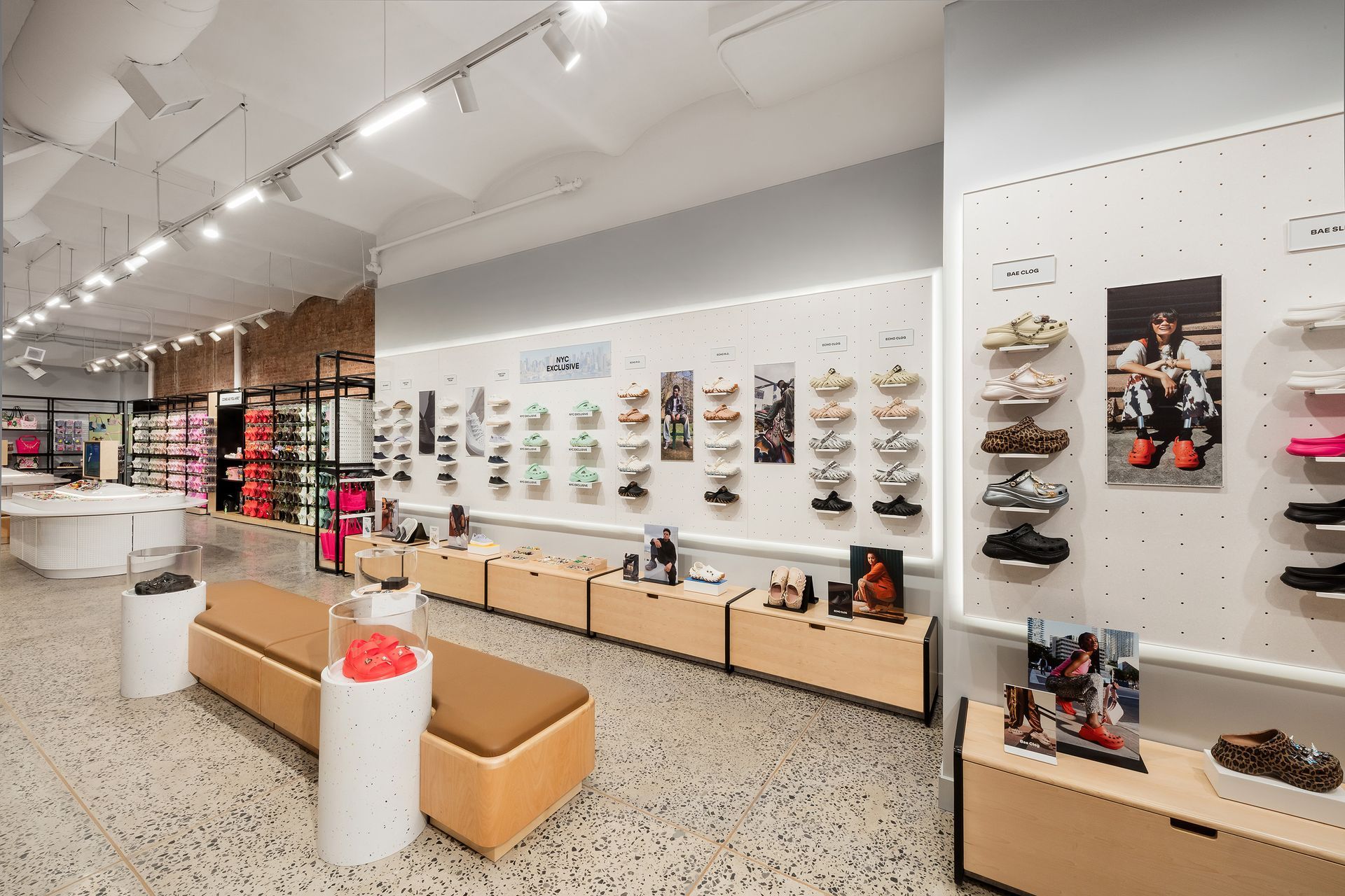 Crocs Shoe store interior: shoes displayed on shelves, wooden benches, bright lighting, and neutral colors.