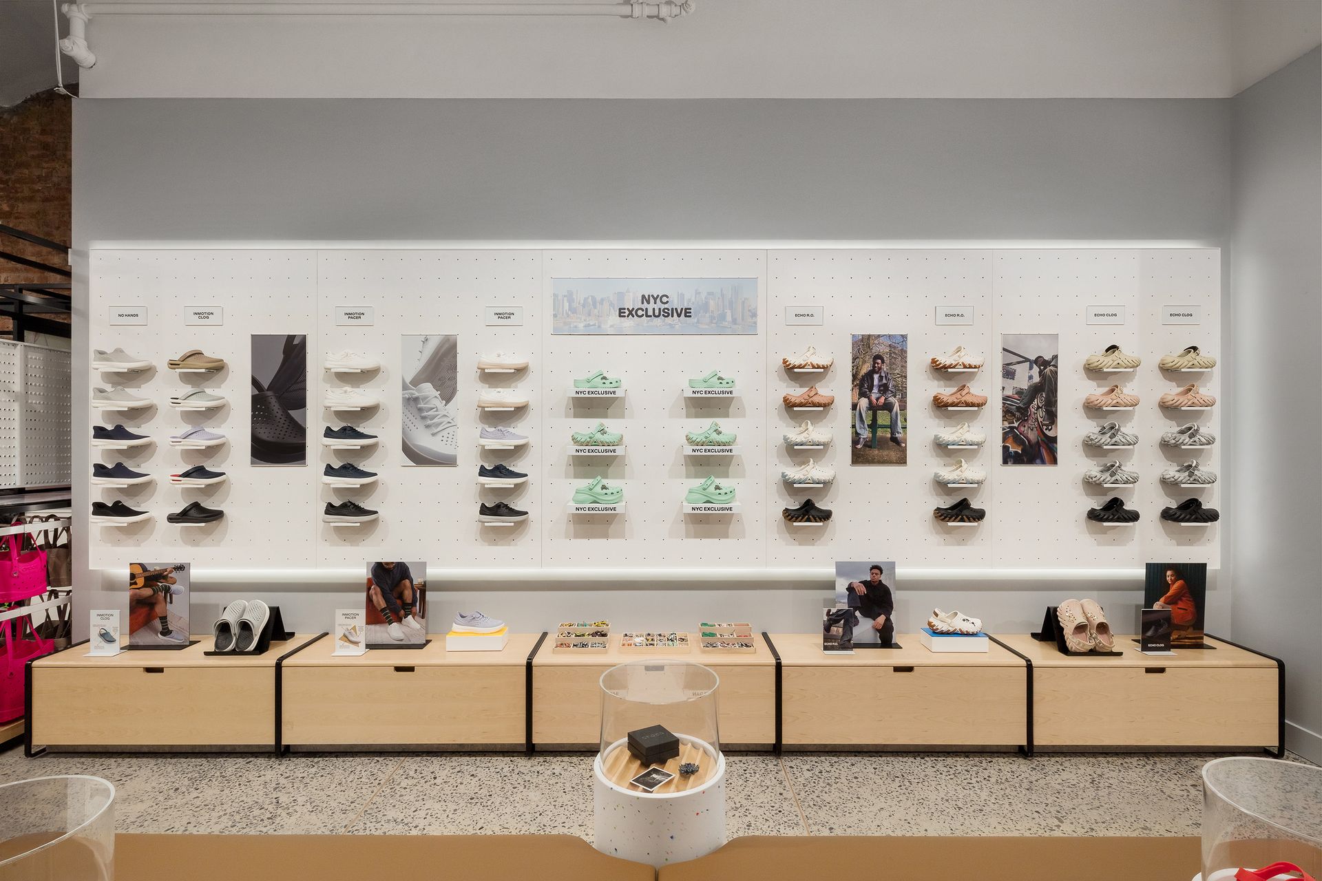 Shoe store display featuring multiple pairs of shoes on wooden shelves and a neutral-colored wall.