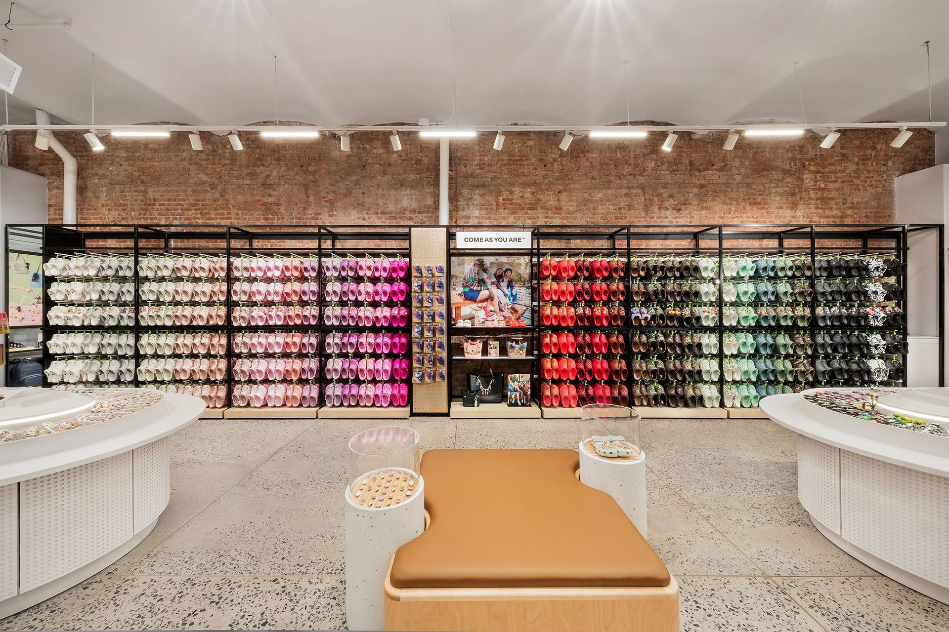 A retail space with colorful shoes displayed on shelves; seating and tables in a modern setting.