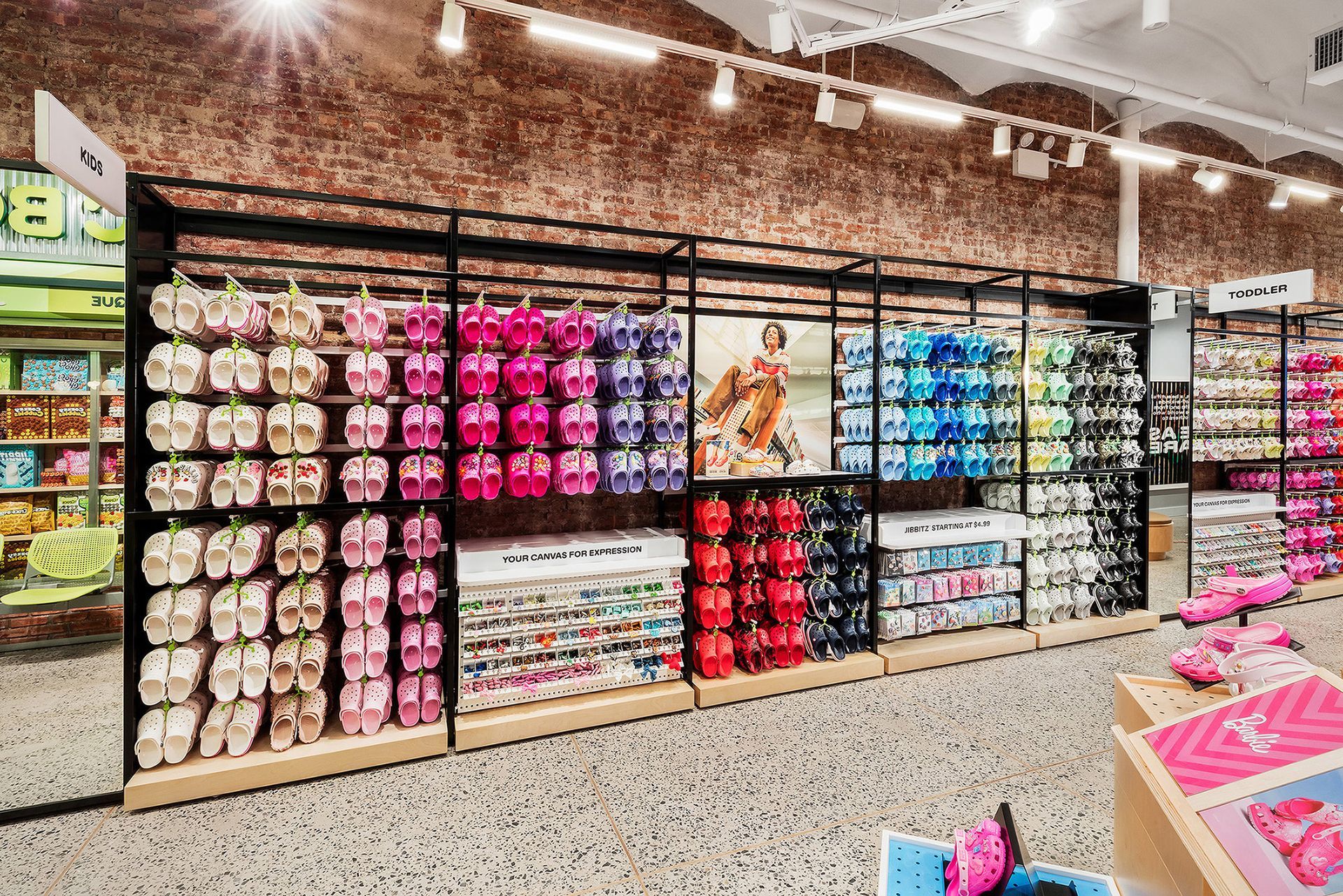 Shelves of colorful shoes in a store, displayed against a brick wall.
