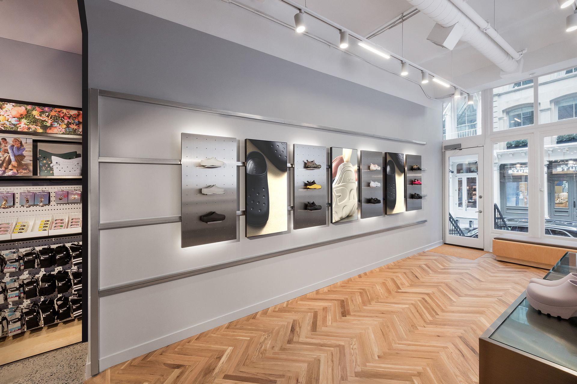 Shoe store interior with wood floors, display panels, and merchandise; natural light through front door.