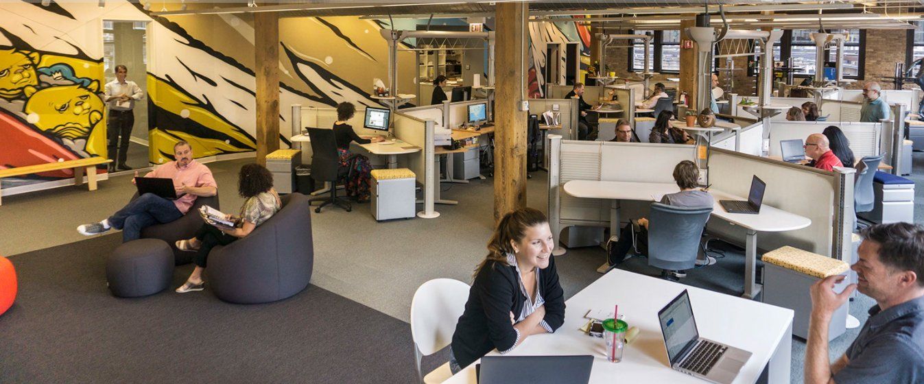 A group of people are sitting at tables in an office.