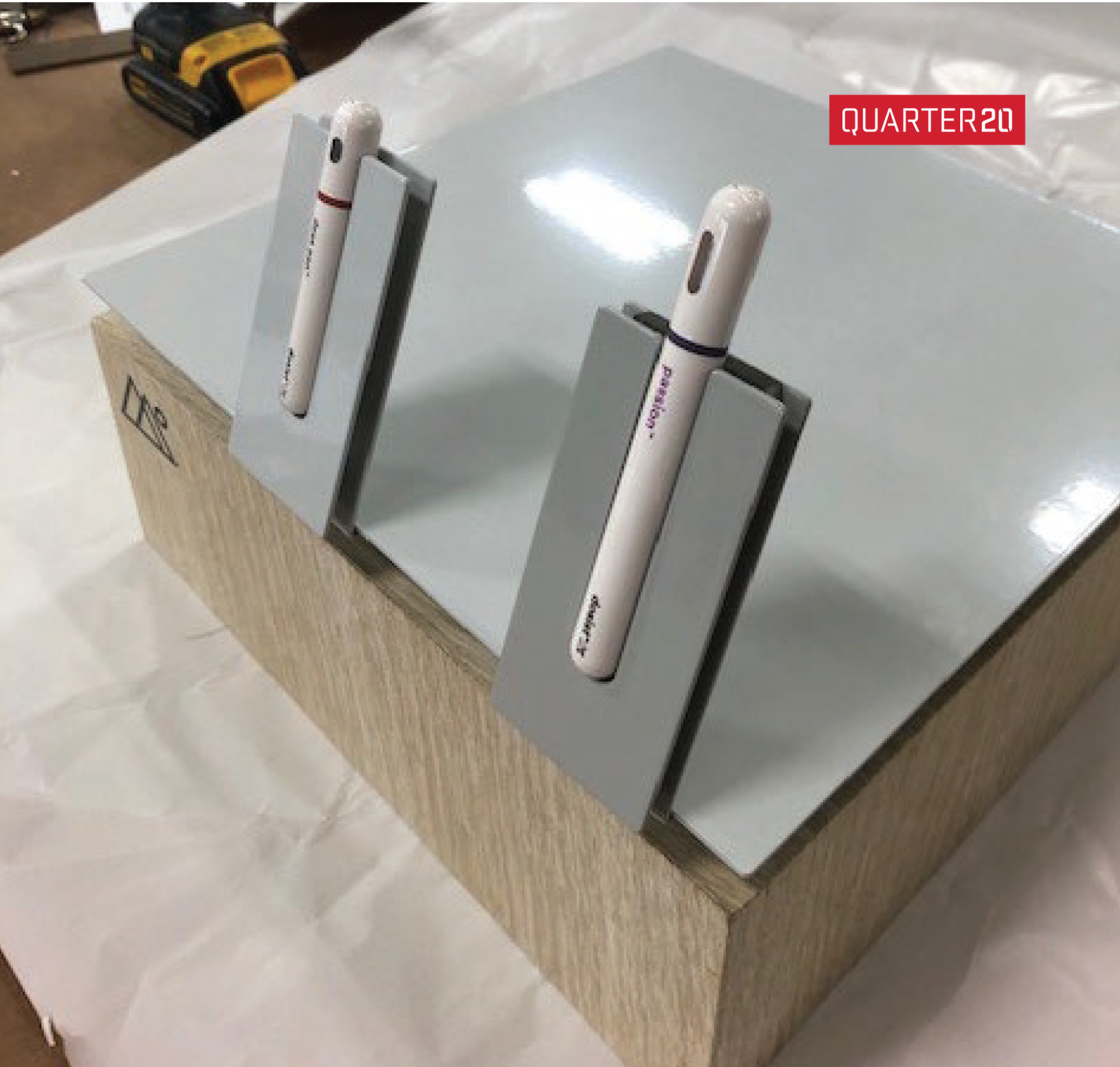 Two pens are sitting on top of a wooden box that says quarter 20