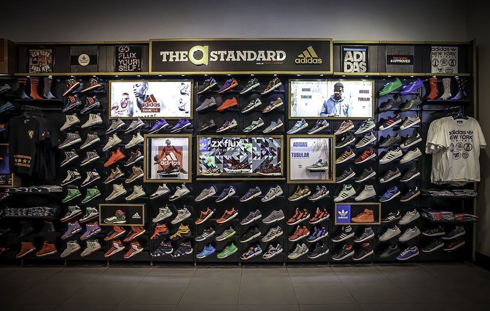 A wall filled with lots of shoes and shirts in a store.