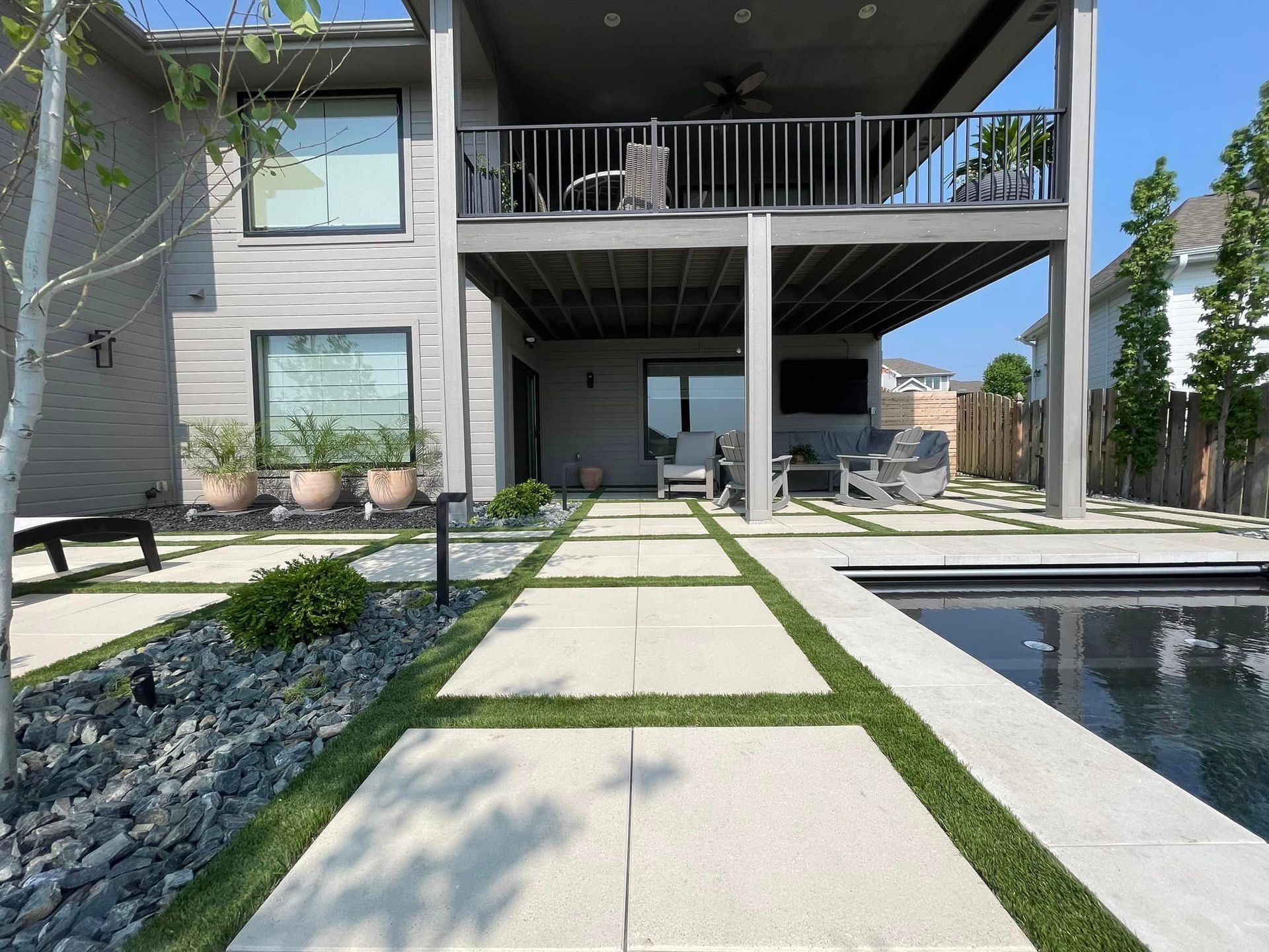 Image of backyard patio in modern style with grass patches between concrete blocks.