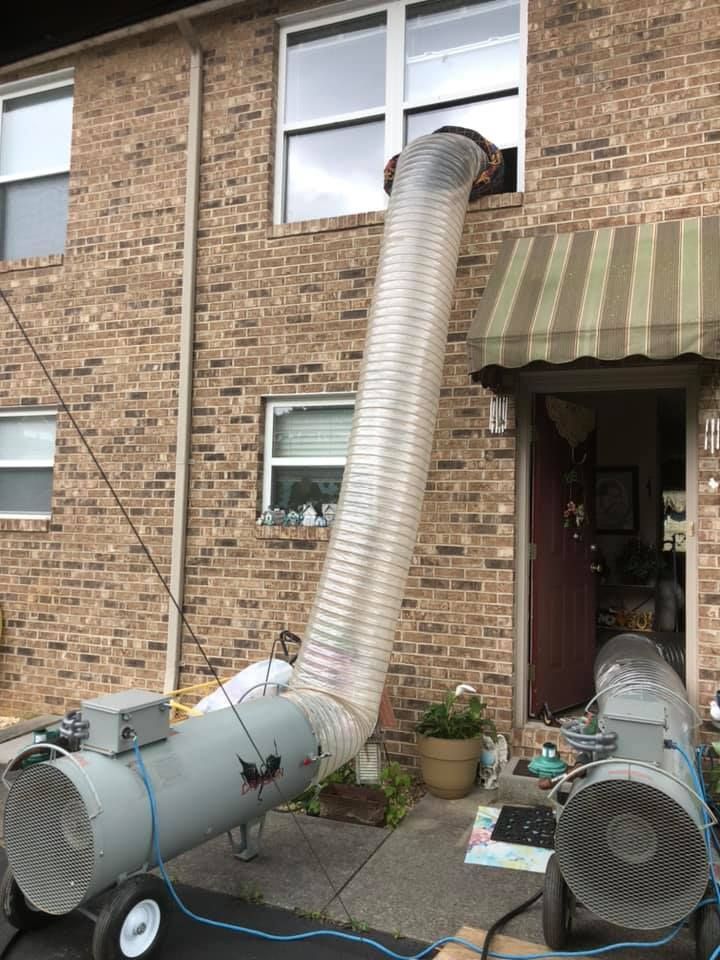 A large hose is attached to the side of a brick building.
