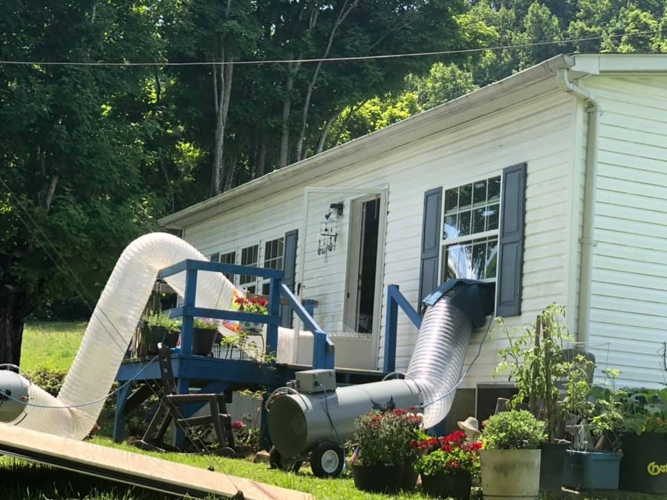 A white house with blue shutters and a hose in front of it