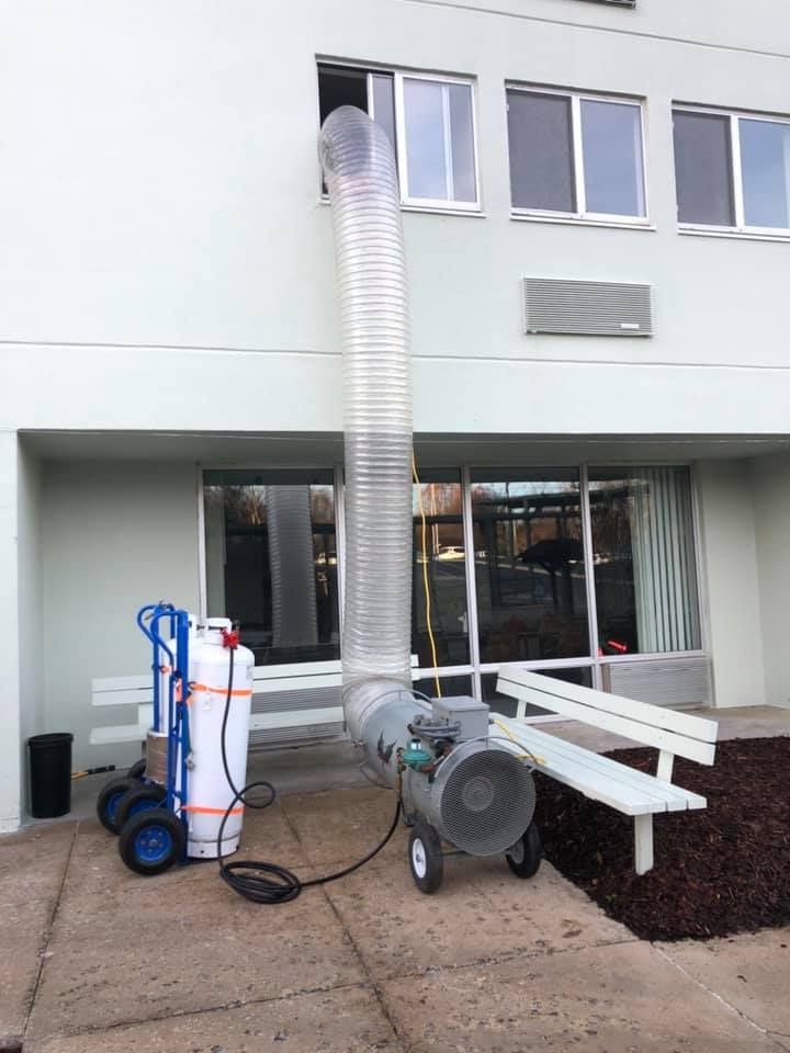 A large hose is attached to a machine outside of a building.